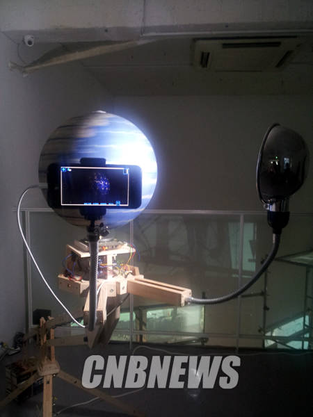 빠르게 돌아가는 지구본 앞에 스마트폰이 설치됐다. 손경환 작가의 '1.3초의 영역에 대한 오러리 모델'은 현대의 정보통신에서 실시간이라고 느끼는 짧은 시간을 표현한다.(사진=김금영 기자)